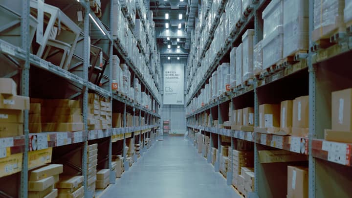 A long aisle of racked pallets in a lit distribution warehouse